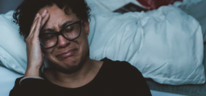 sad man sitting against a bed